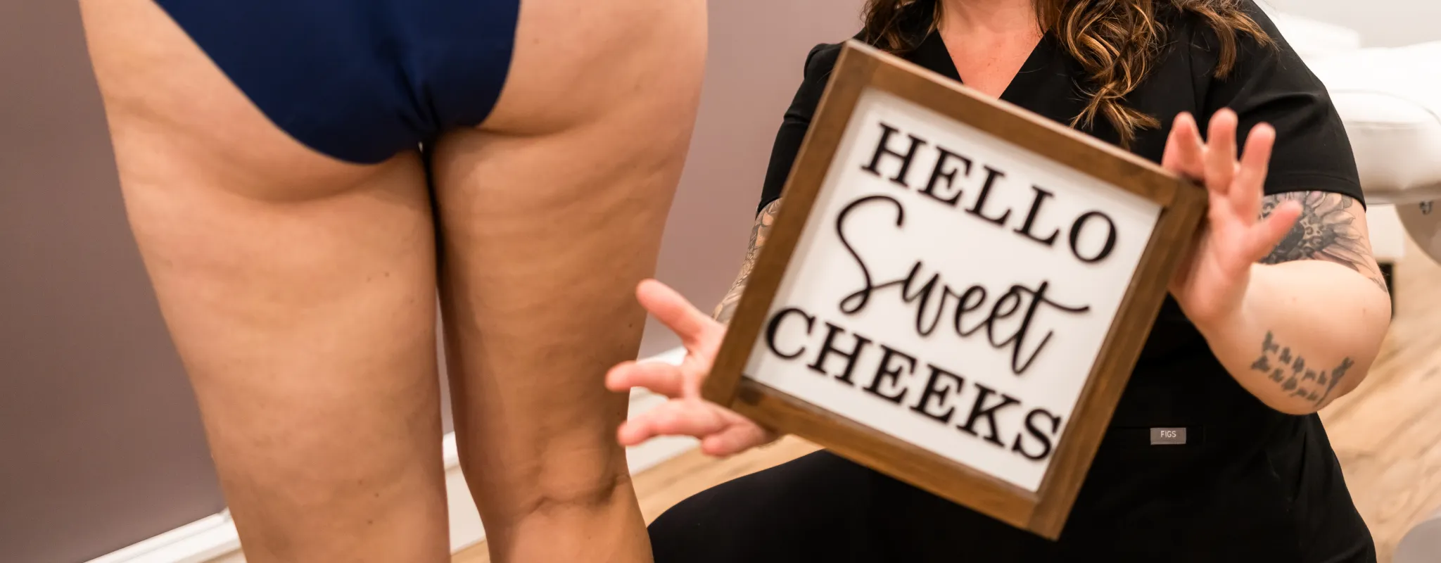 Brookes holding a sign that says sweet cheeks with a person showing a bum in blue underwear